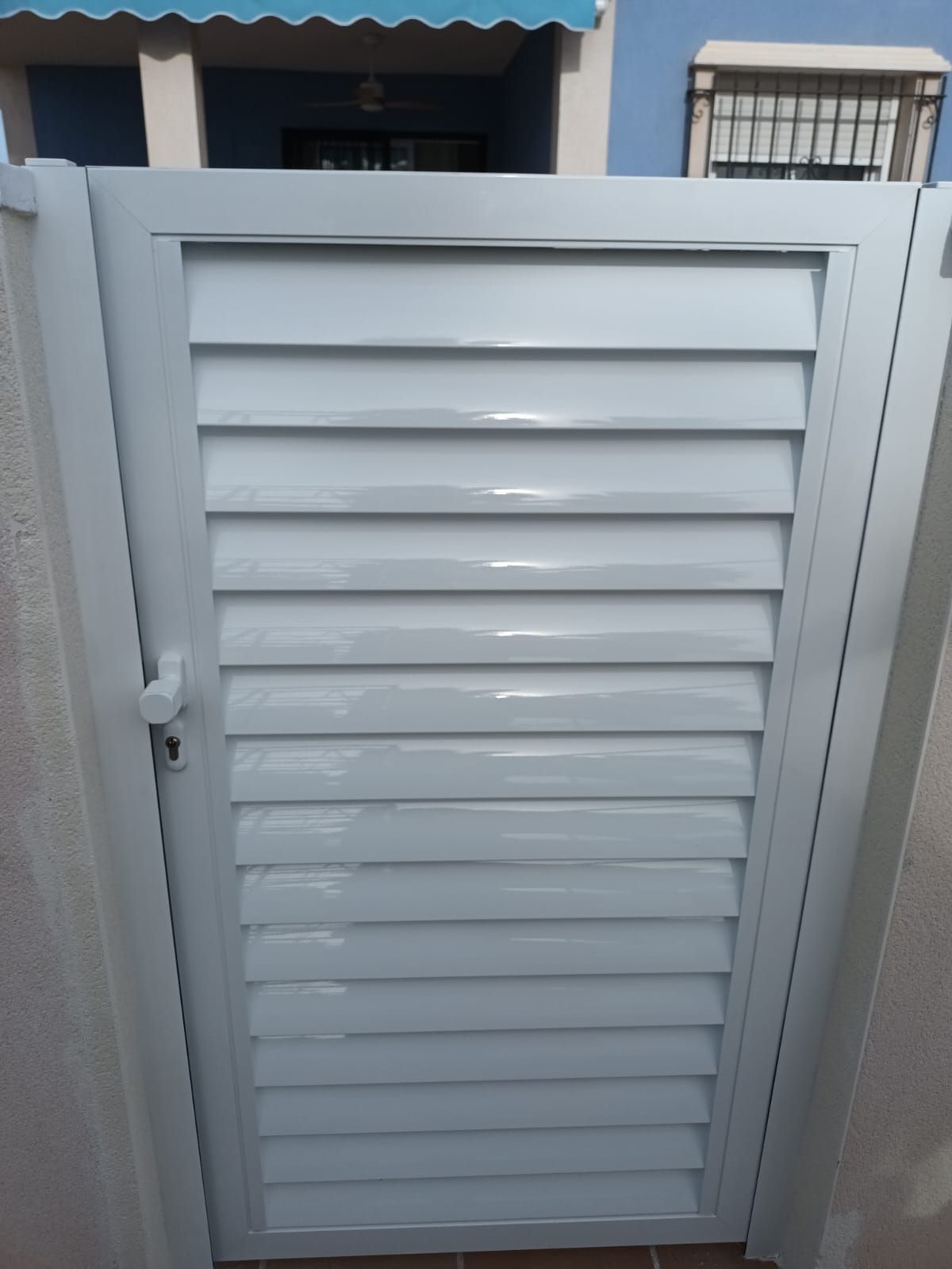 Una puerta blanca con persianas conduce a una casa.