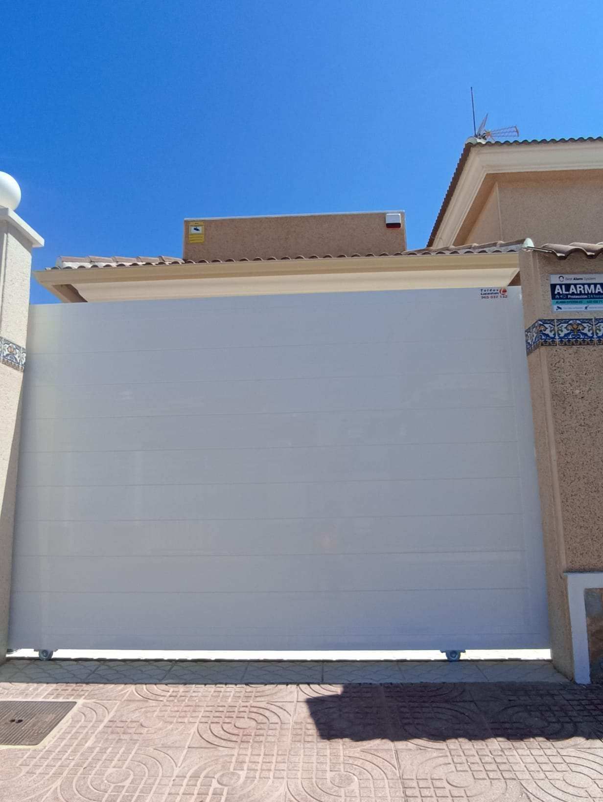 Una puerta de garaje corrediza blanca está abierta frente a una casa.