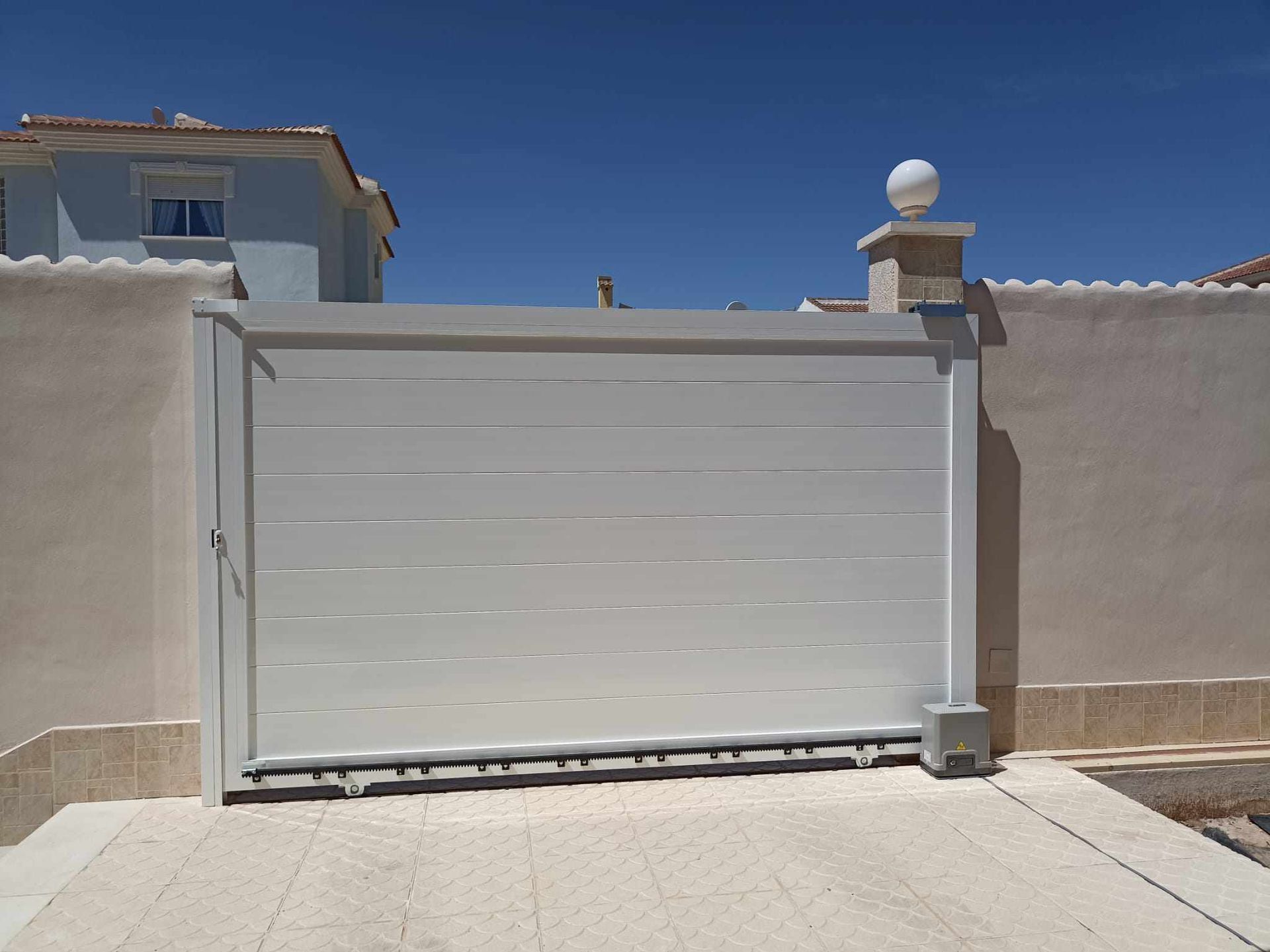 Una puerta corrediza blanca está abierta frente a una casa.