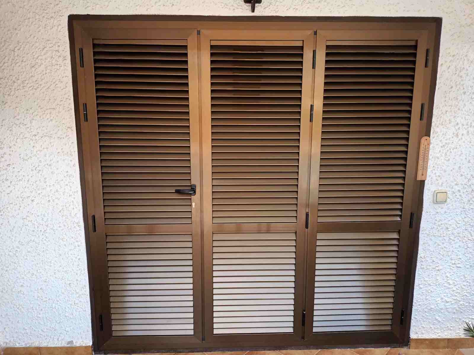 Una puerta de madera con contraventanas está contra una pared blanca.