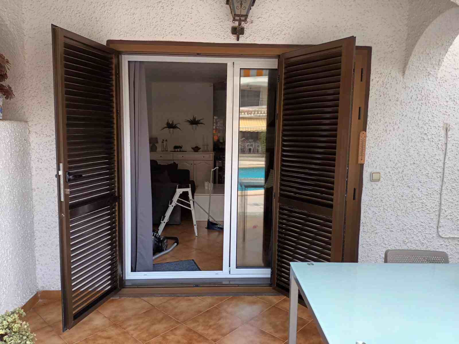 Un patio con una mesa y una puerta corrediza de vidrio que conduce a una sala de estar.