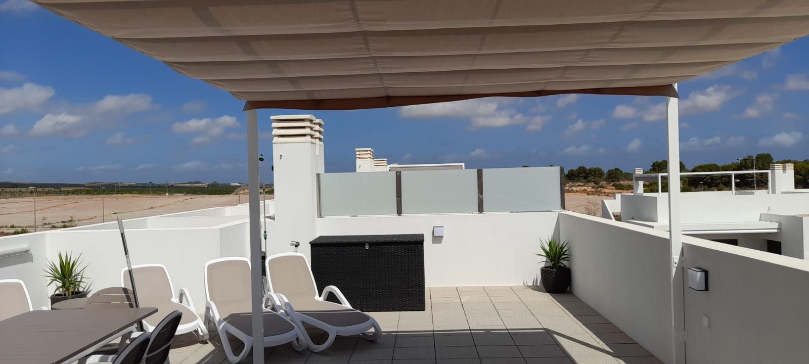 Una terraza en la azotea con una mesa y sillas bajo un dosel.