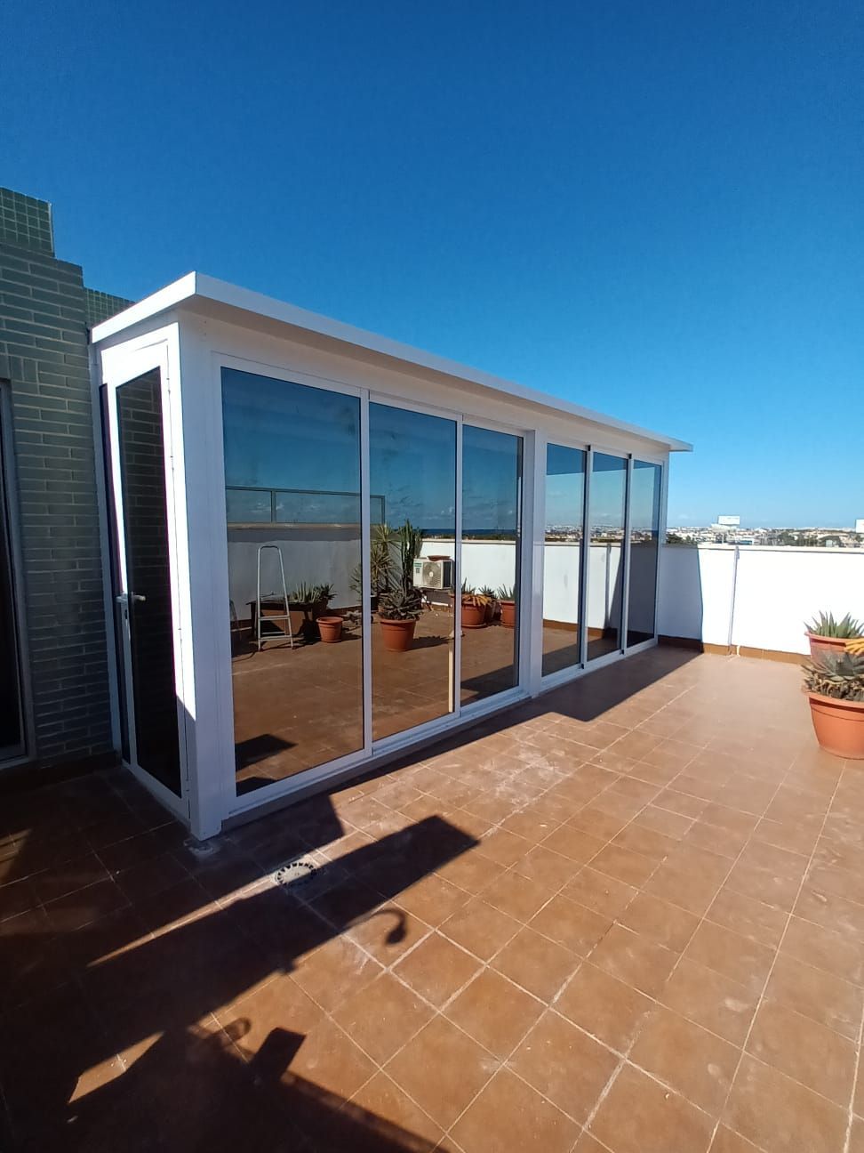 Un edificio blanco con muchas ventanas está ubicado encima de un patio de baldosas.