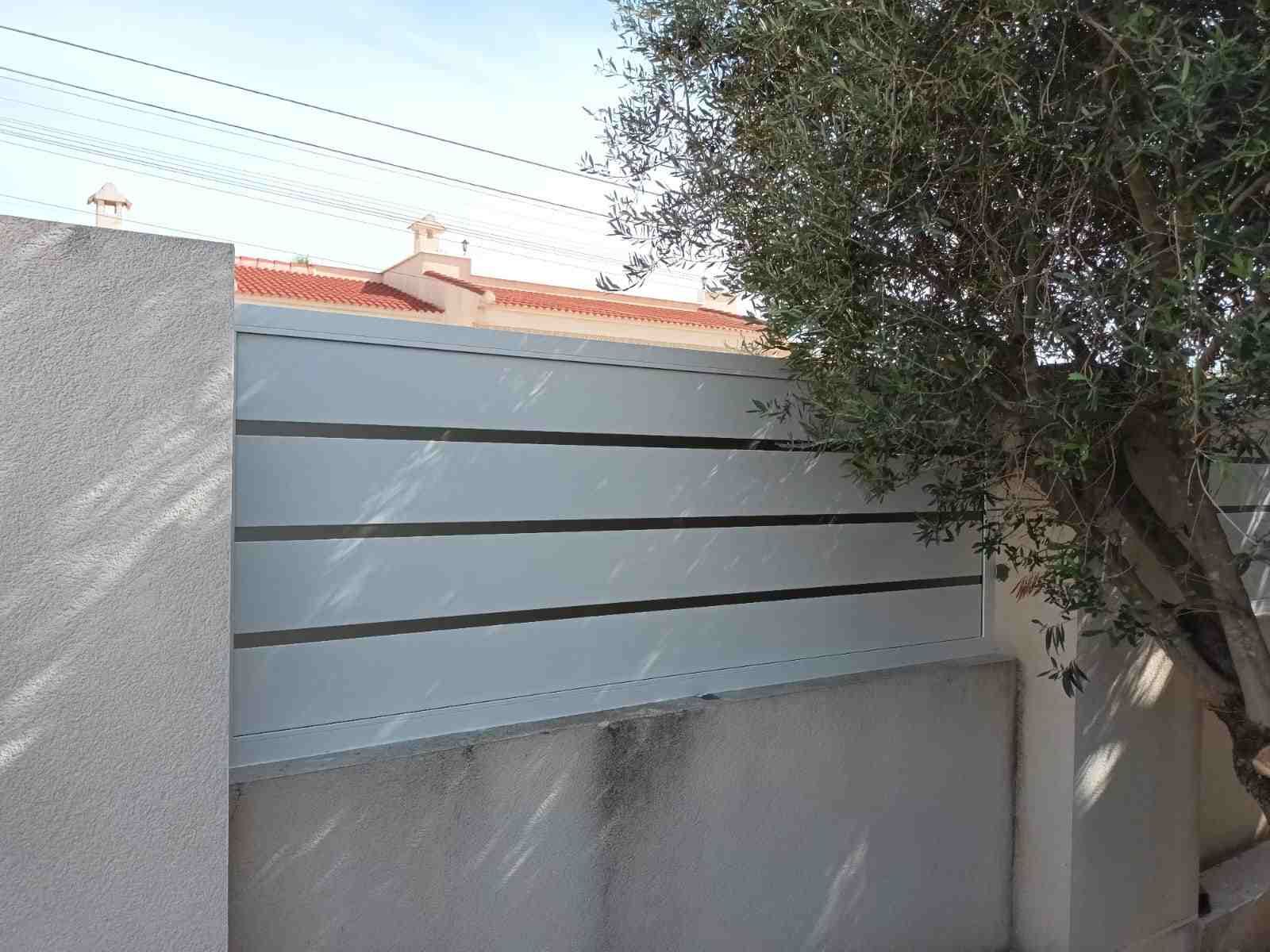 Una valla blanca con un árbol delante de ella.