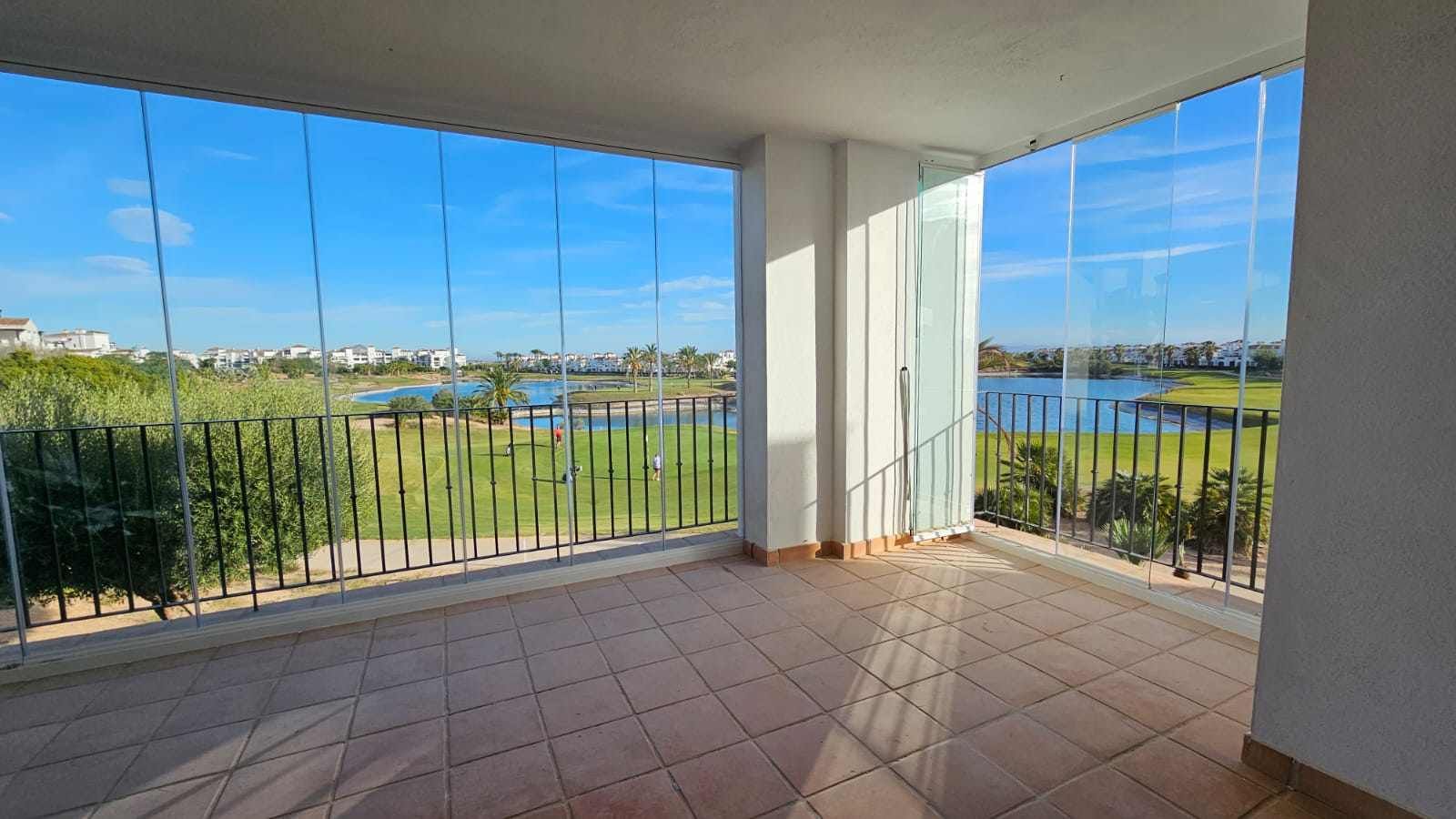 Una habitación vacía con balcón y vista a un campo de golf.