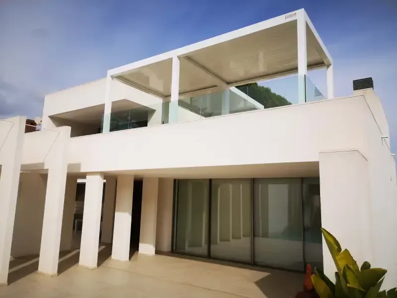 Una casa blanca con una pérgola encima.