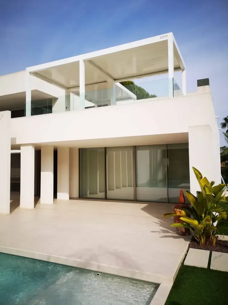 Una casa blanca con una piscina delante de ella.