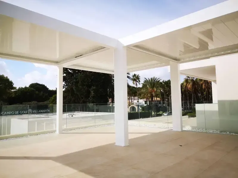 Una pérgola blanca se encuentra en la parte superior de un patio al lado de una piscina.