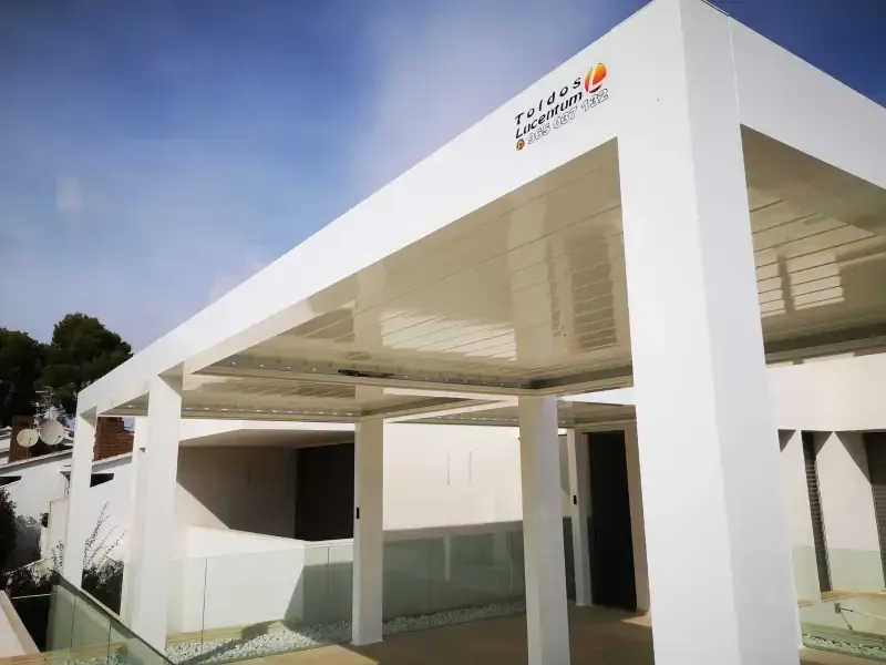 Un edificio blanco con una pérgola encima.