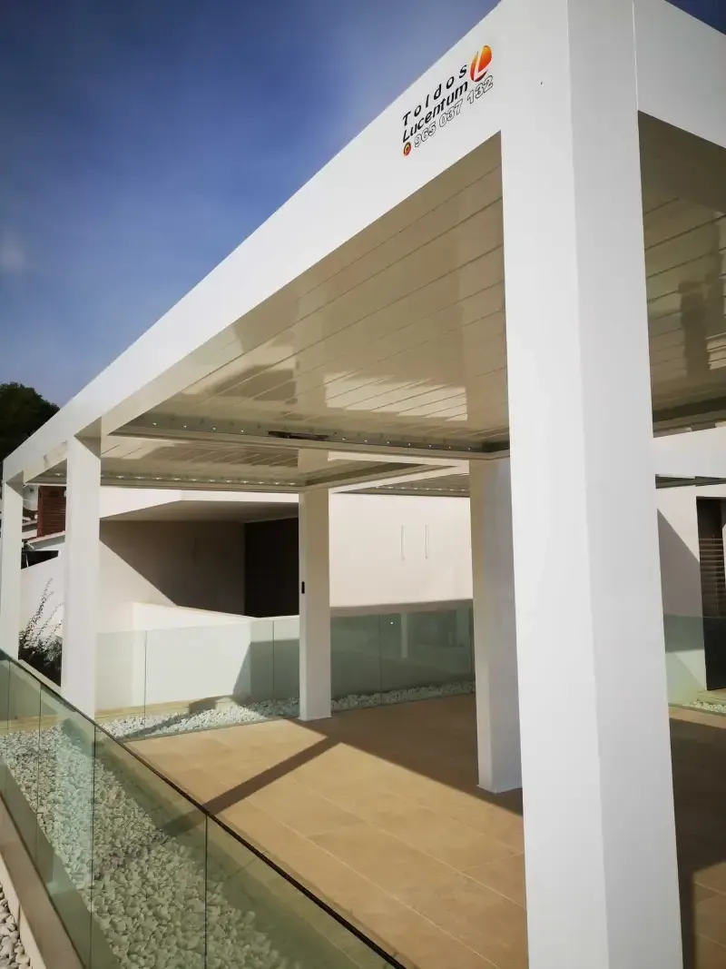 Un edificio blanco con una barandilla de cristal y un techo.