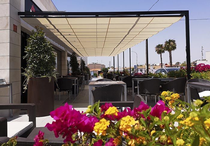 Un restaurante con mesas y sillas bajo un dosel con flores en primer plano.