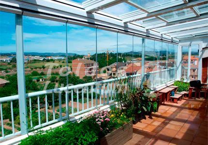 Un balcón con muchas ventanas y plantas.