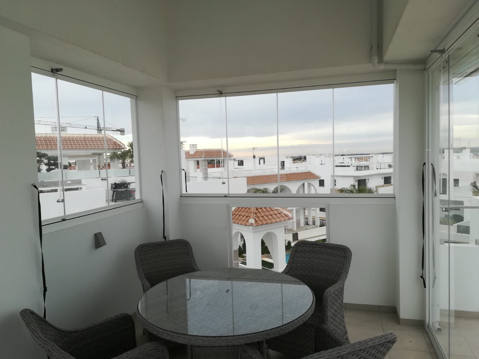 Una mesa y sillas en un balcón con vista a una ciudad.