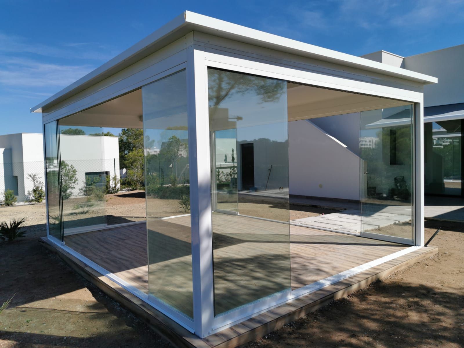 Una casa blanca con una pérgola de cristal delante de ella.