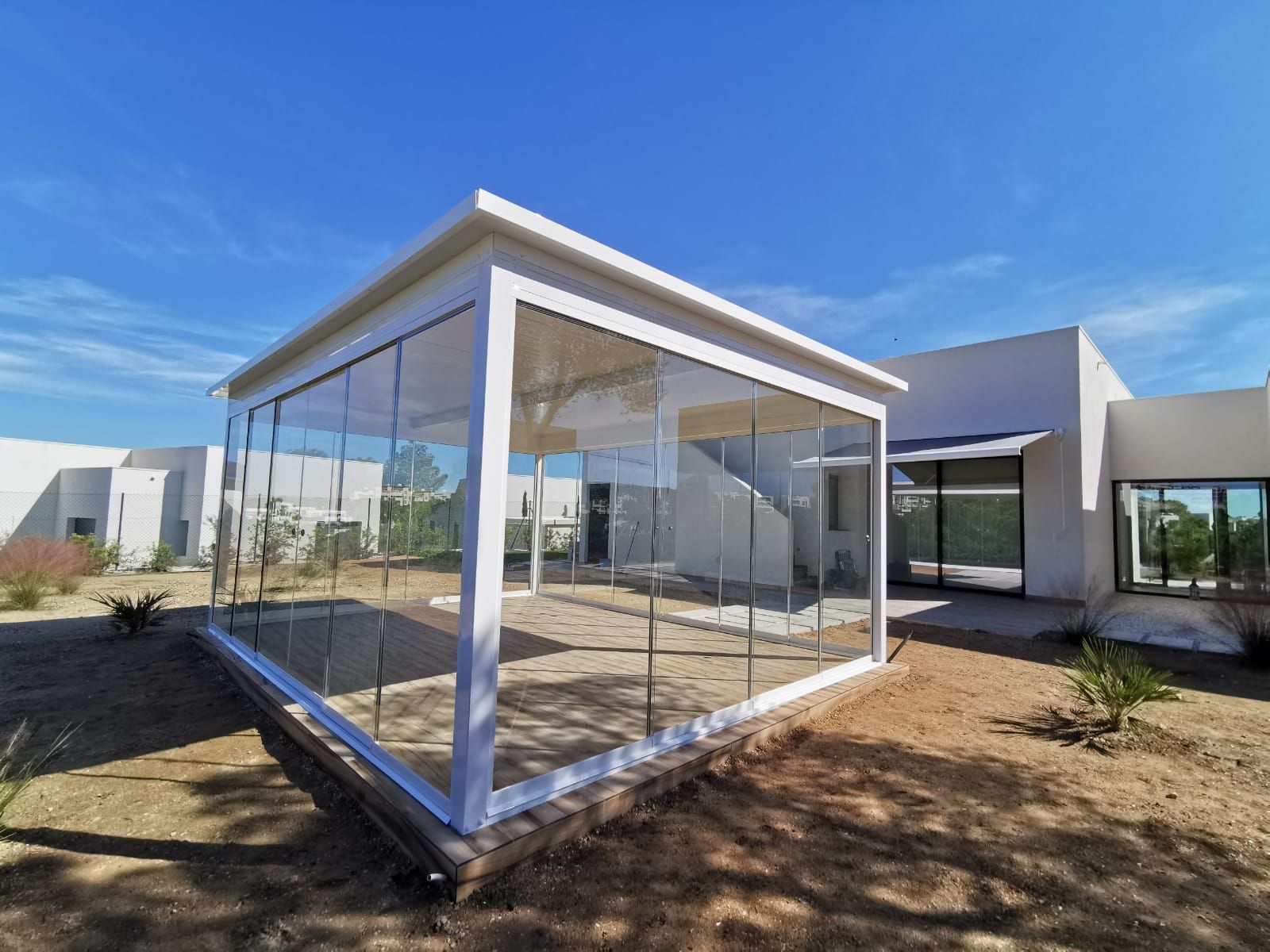 Una casa blanca con un patio de cristal delante de ella.