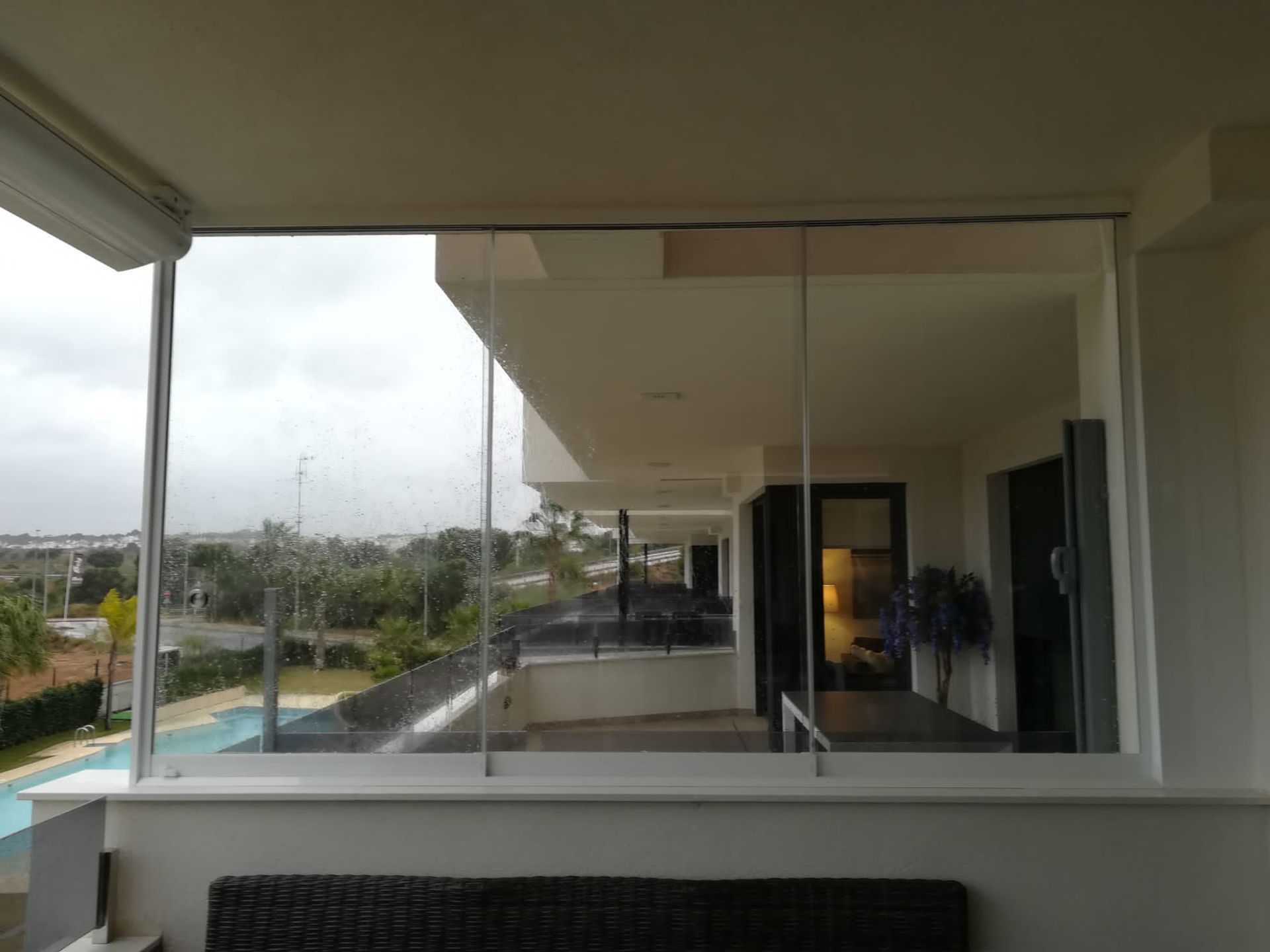 Un balcón con sofá y vista a una piscina.