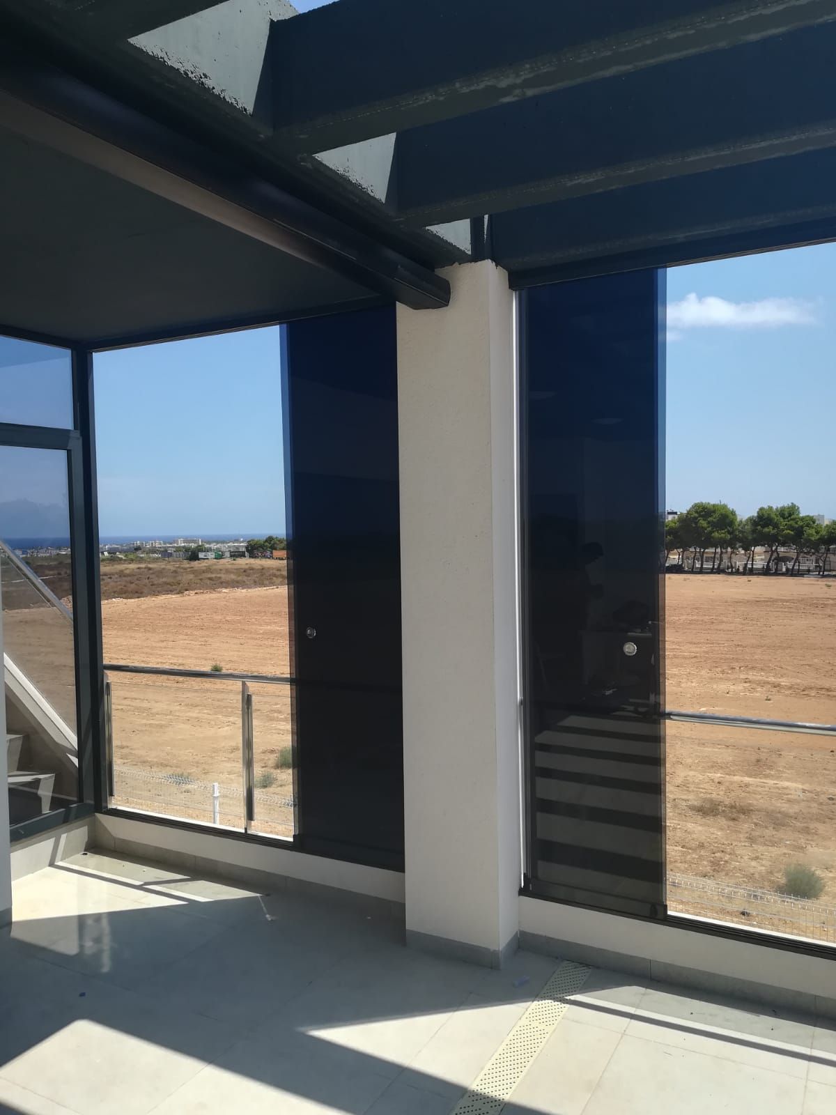 Una habitación con muchas ventanas y vista a un campo.
