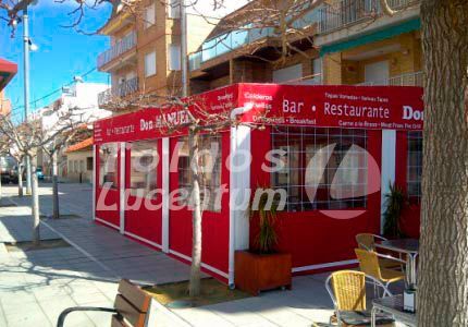 Un edificio rojo con mesas y sillas delante.