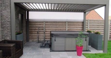 Un jacuzzi está debajo de una pérgola en un patio trasero.