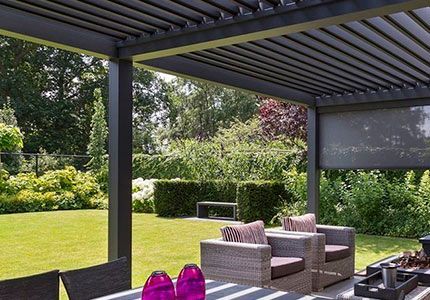 Un patio con una mesa y sillas bajo una pérgola.