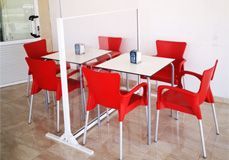 Una habitación con sillas y mesas rojas y un divisor.