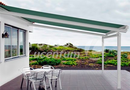 Un patio con un toldo verde encima y una mesa y sillas.