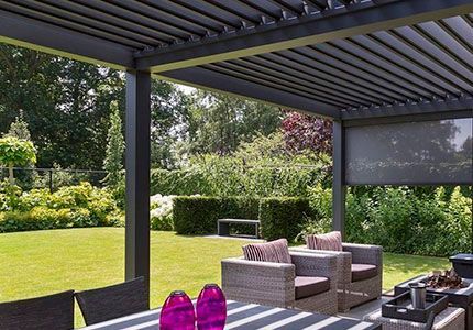 Un patio con una mesa y sillas bajo una pérgola.