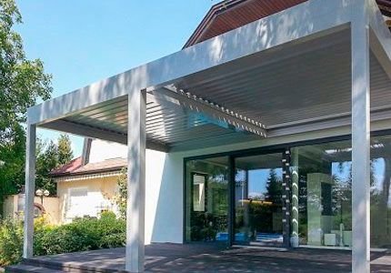 Una casa con una pérgola al costado.