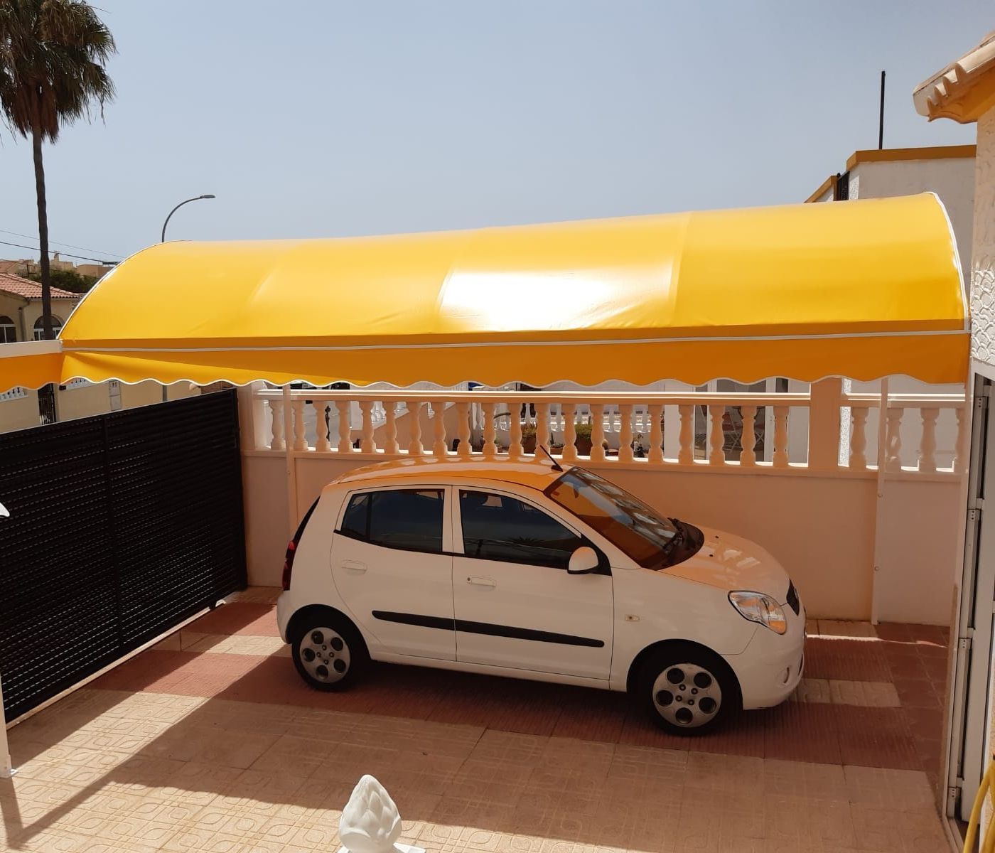 Un coche blanco está aparcado bajo un toldo amarillo.