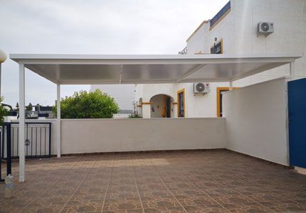Un edificio blanco con una pérgola encima.
