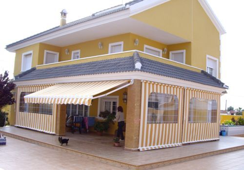 Una casa amarilla con un toldo a rayas en el porche