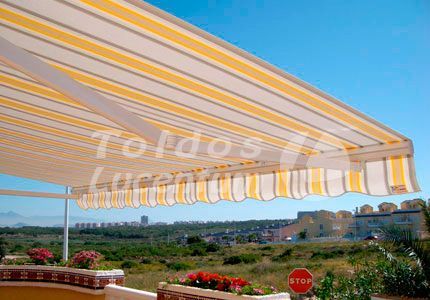 Un toldo de rayas amarillas y blancas cuelga sobre un balcón.