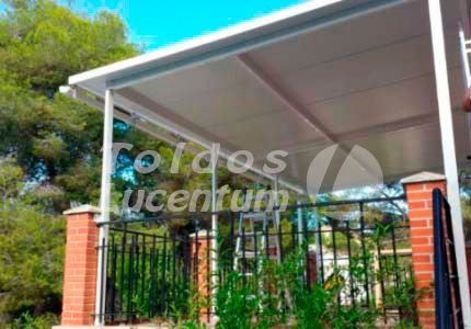 Un toldo blanco se encuentra encima de un edificio de ladrillos al lado de una valla.