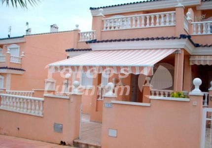 Una casa rosa con un toldo blanco en el porche