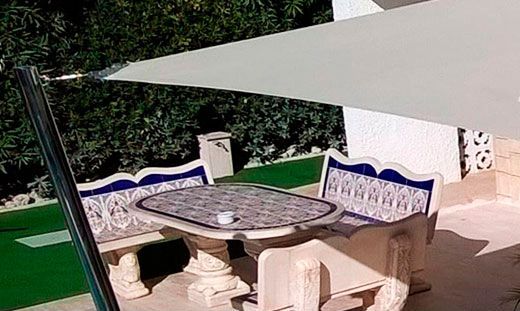 Un patio con una mesa y sillas bajo una sombrilla.