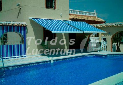 Una casa con un toldo azul sobre una piscina