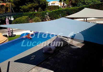 Una gran sombrilla blanca está junto a una piscina.