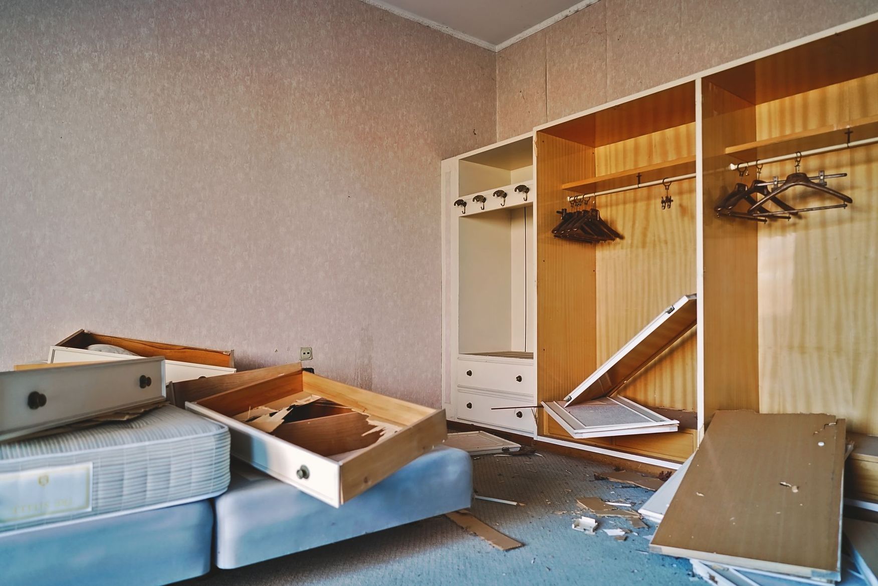 Chambre en désordre avec une armoire ouverte, des tiroirs renversés et un lit recouvert de bric-à-brac.