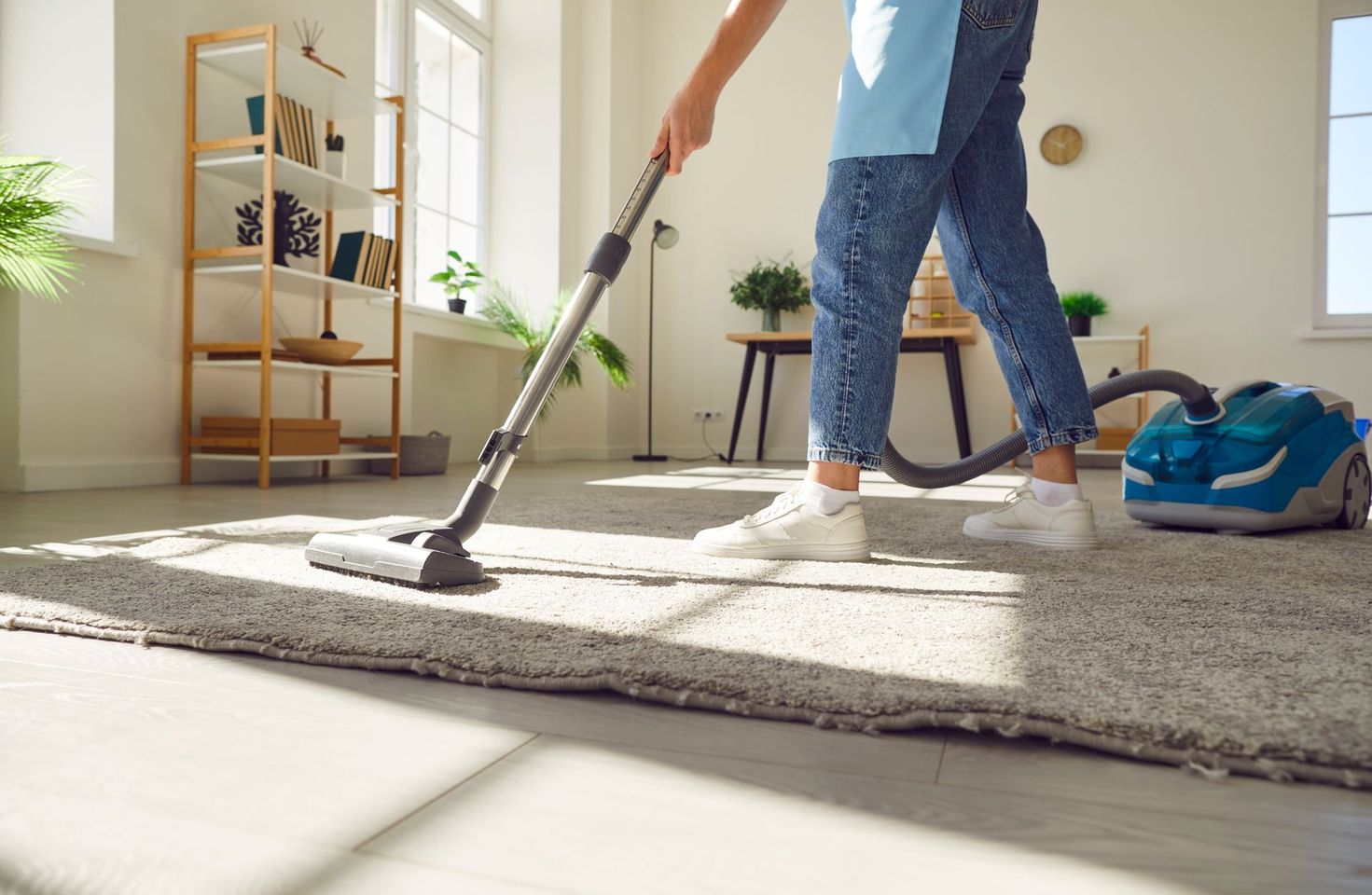 Personne passant l'aspirateur sur un tapis clair dans un salon lumineux