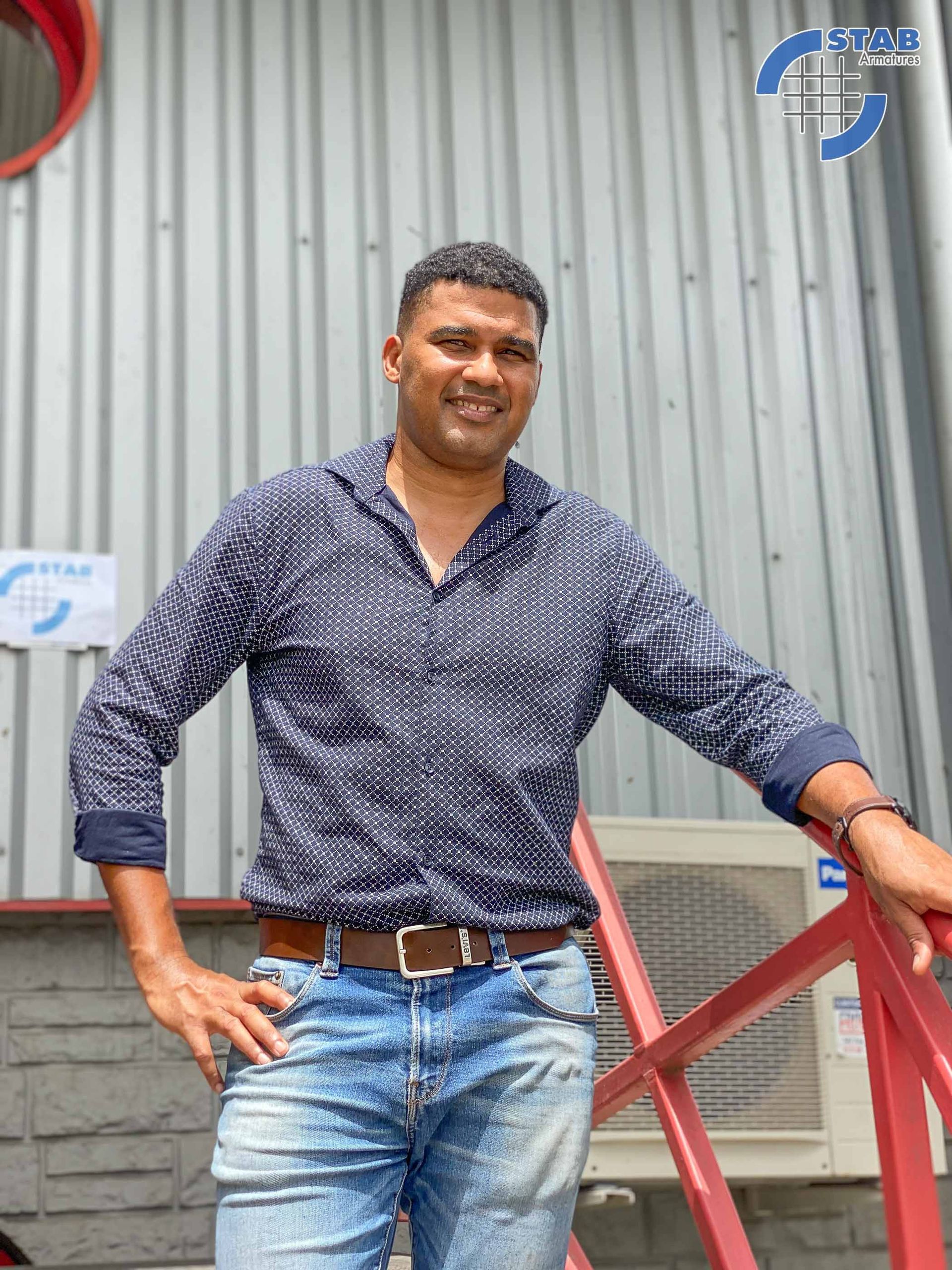 Artisan qui pose à l'extérieur des ateliers