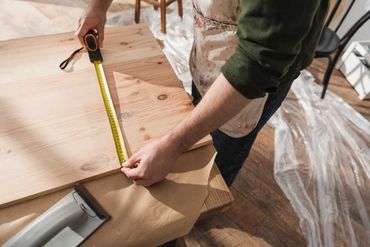 Una persona está midiendo un trozo de madera con una cinta métrica.