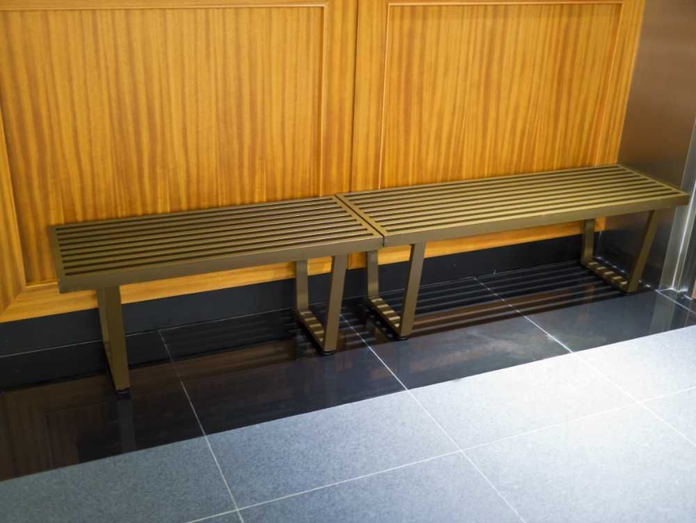 Dos bancos de metal están ubicados uno al lado del otro sobre un piso de baldosas.