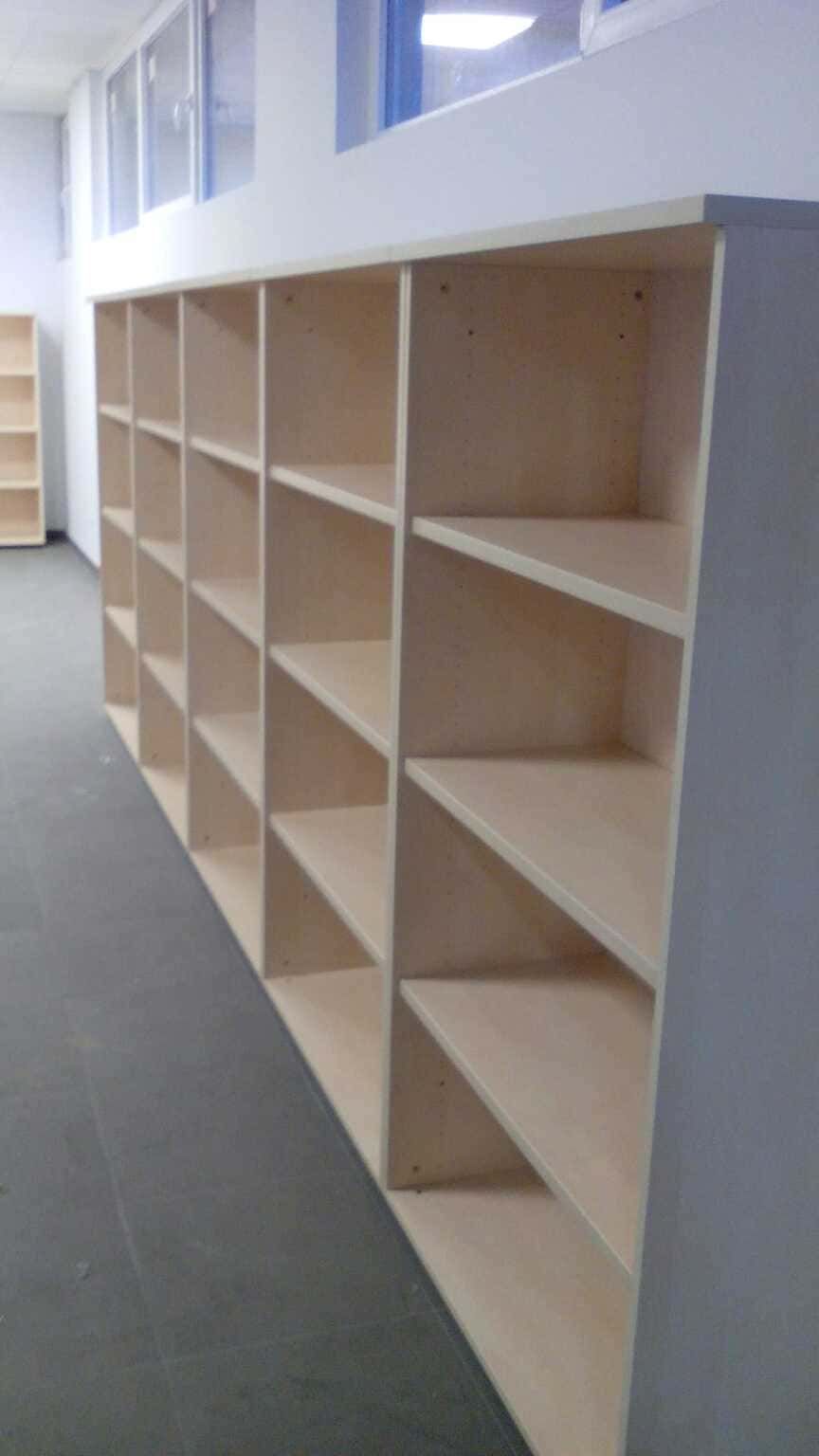 Una fila de estantes de madera en un pasillo junto a una ventana.