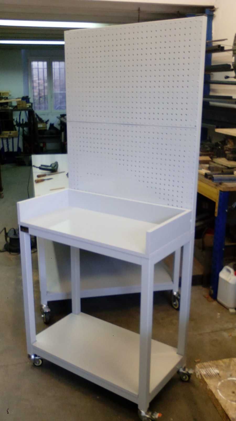 Un banco de trabajo blanco con ruedas y un tablero perforado detrás.