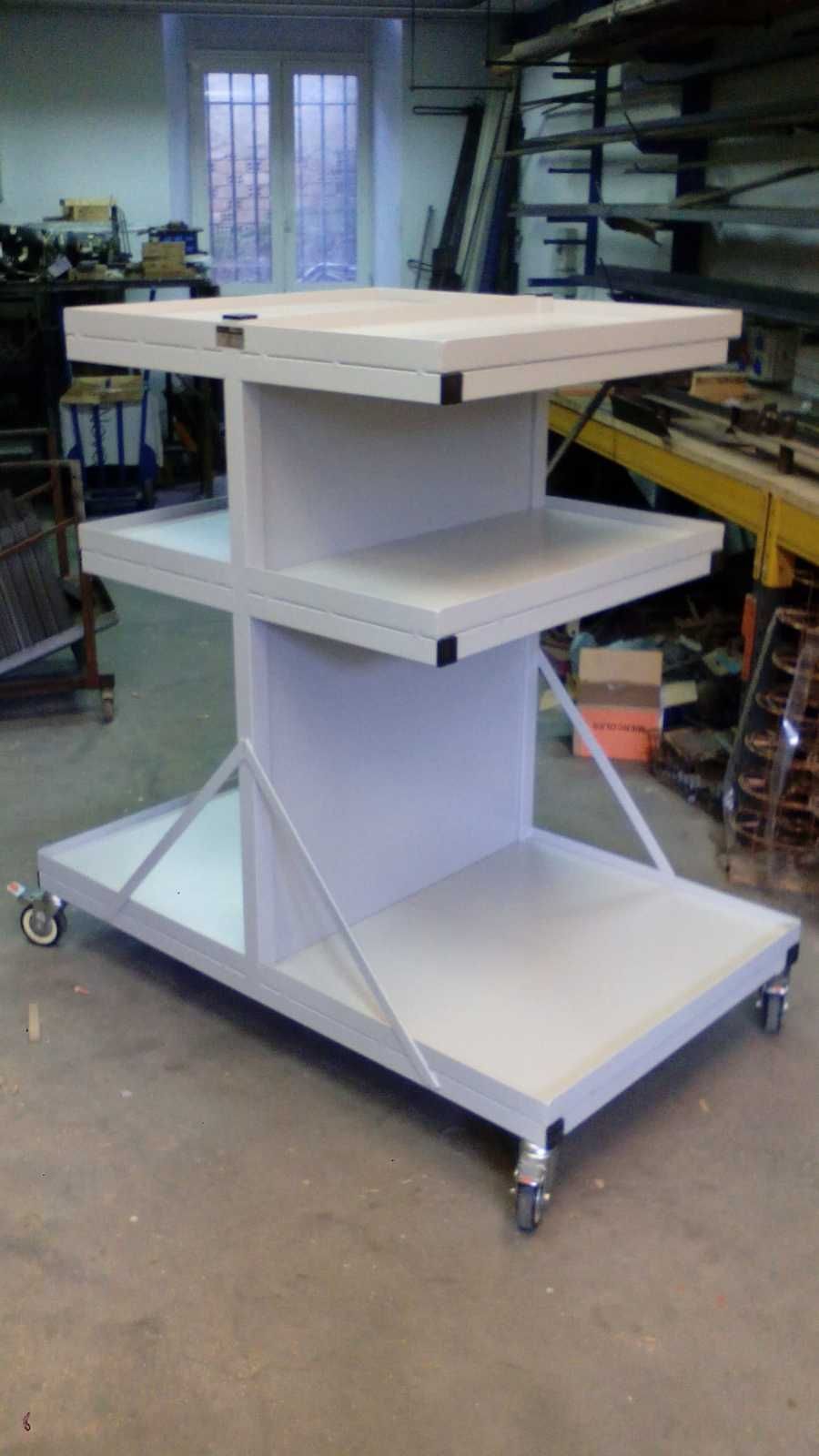 Un carrito blanco con tres estantes y ruedas en una habitación.