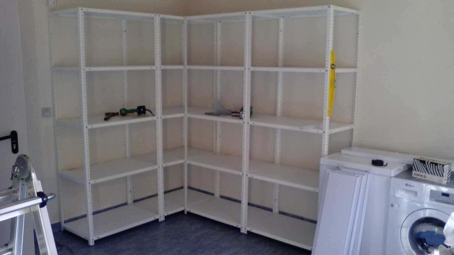 Un lavadero con estantes, una escalera y una lavadora.