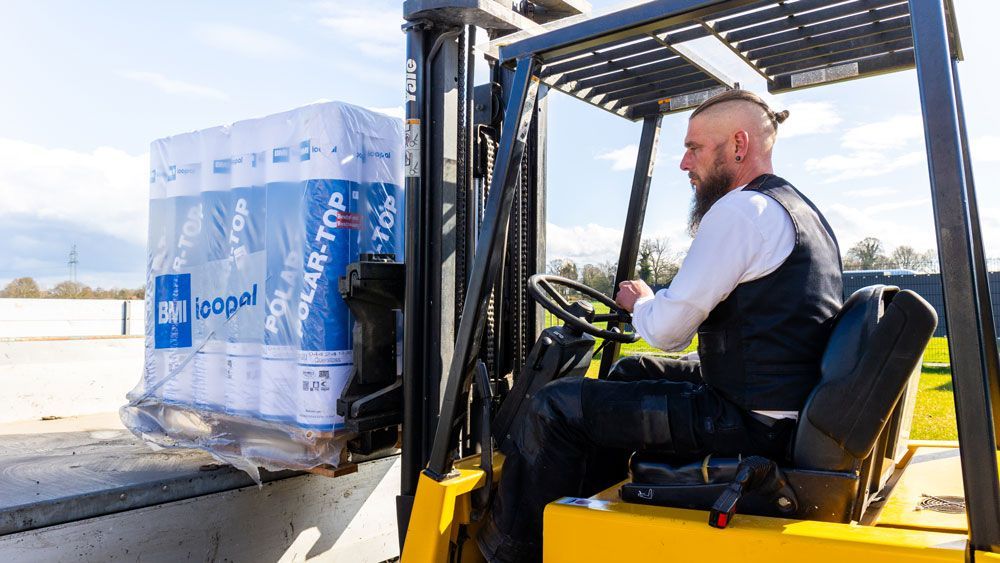 Ein Mann fährt einen Gabelstapler und transportiert eine Palette Toilettenpapier.