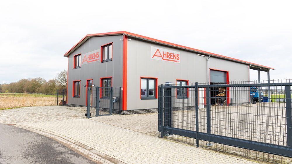 Ein großes grau-rotes Gebäude mit einem Schiebetor davor.