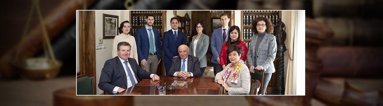 Grupo de personas vestidas de negocios reunidas alrededor de una mesa; entorno de una oficina de abogados.