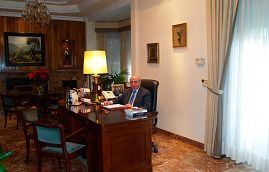 Hombre sentado en un escritorio de oficina. Escritorio de madera, chimenea y decoración ornamentada.